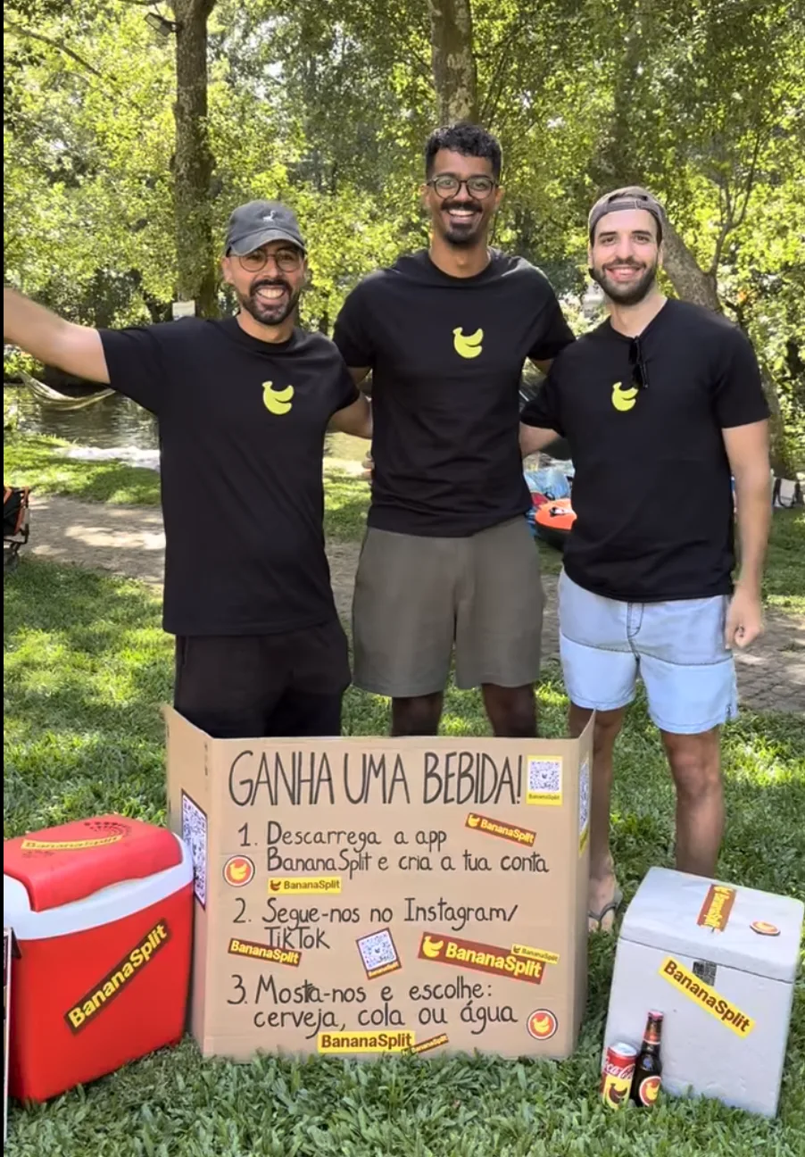 Three friends from the BananaSplit team beside the campaign sign