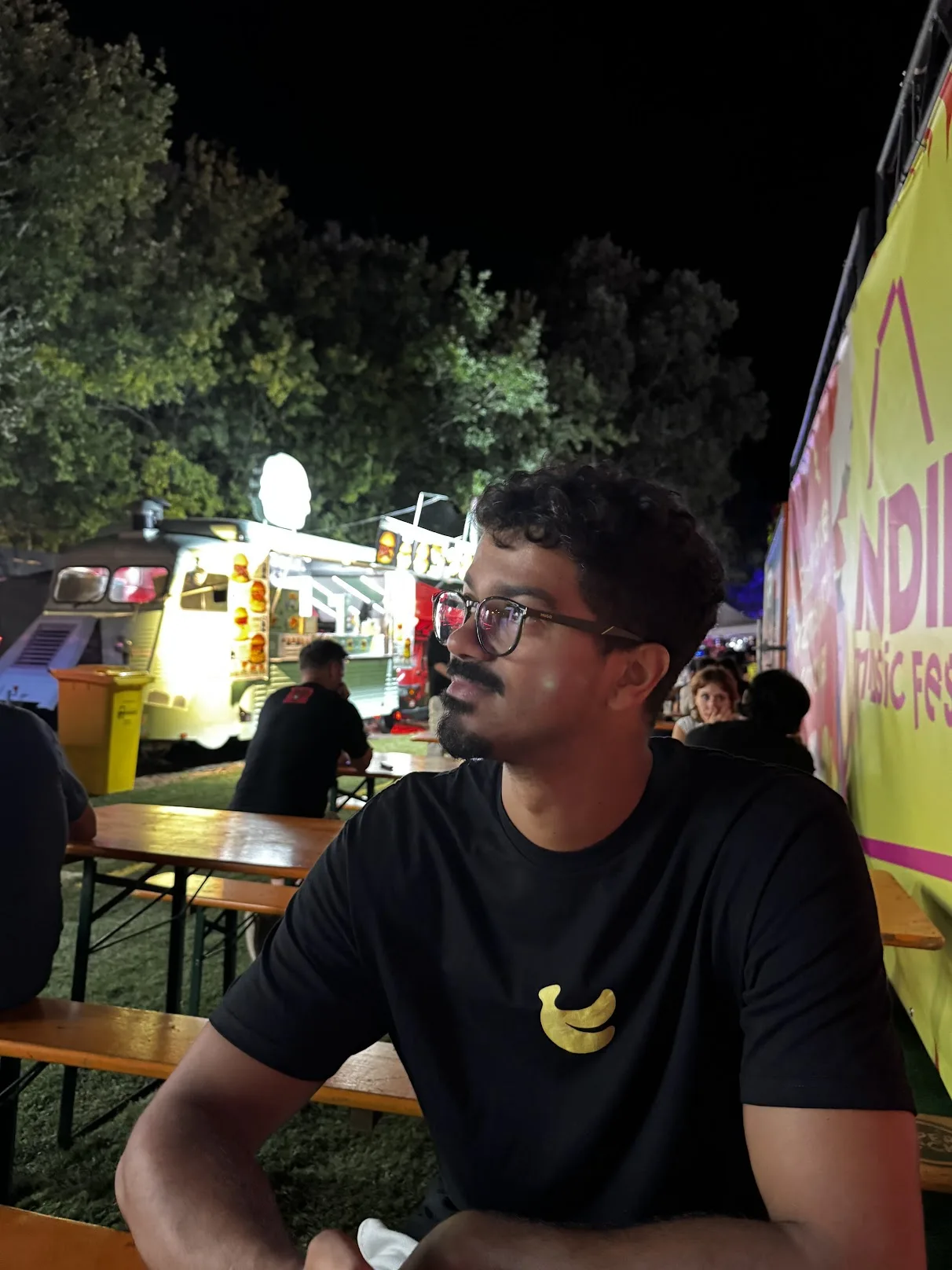 Leo sentado na zona de restauração do Indie Music Fest à noite