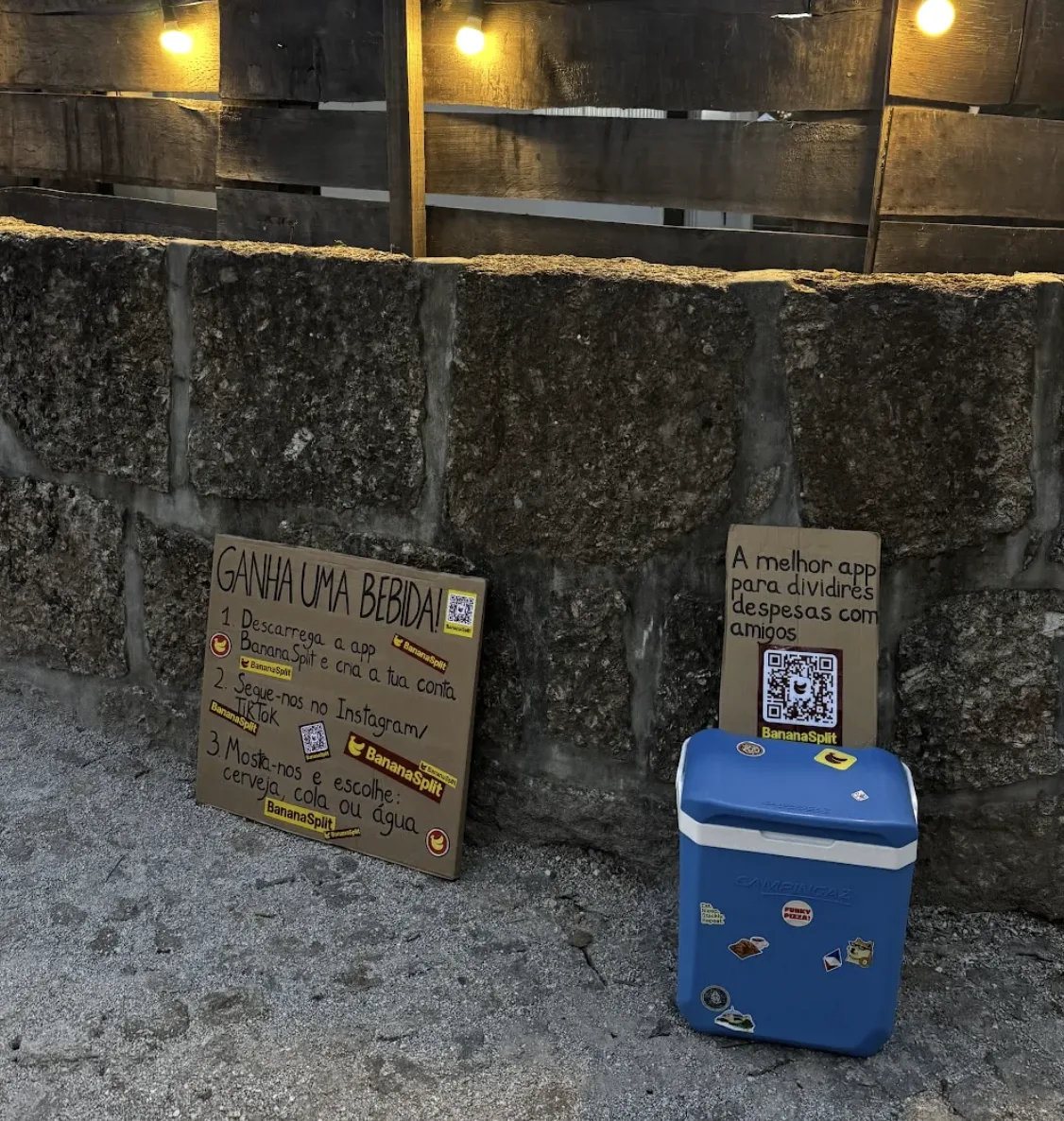 Geleira azul e dois cartazes do BananaSplit encostados ao muro junto à entrada do festival