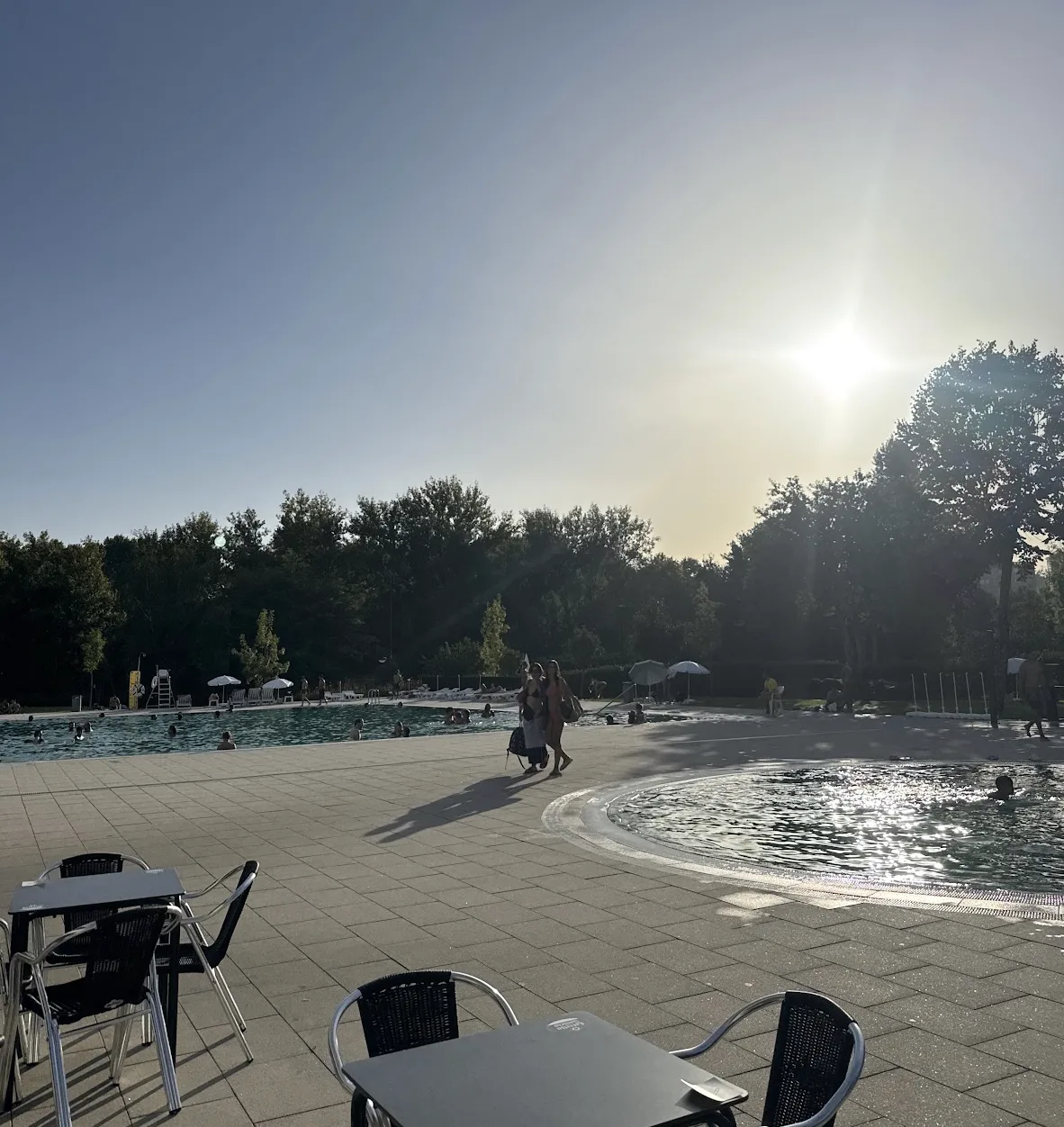 Piscinas e esplanada da Piscina Verde ao fim da tarde, com banhistas e árvores à volta