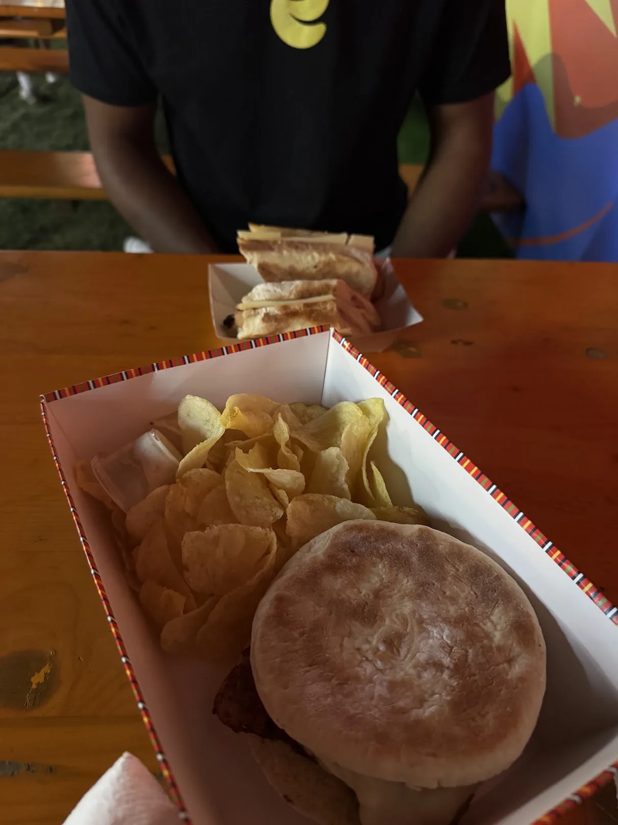 Sandes e batatas fritas numa mesa de madeira dentro do festival