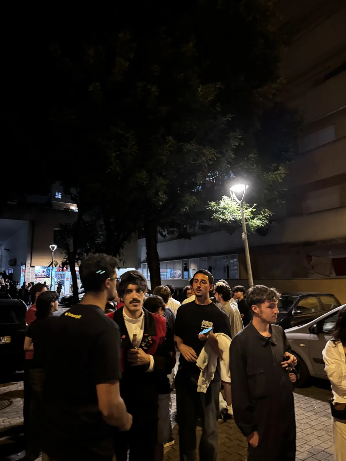 La calle de los bares de la UM de noche, con estudiantes pasando bajo las farolas