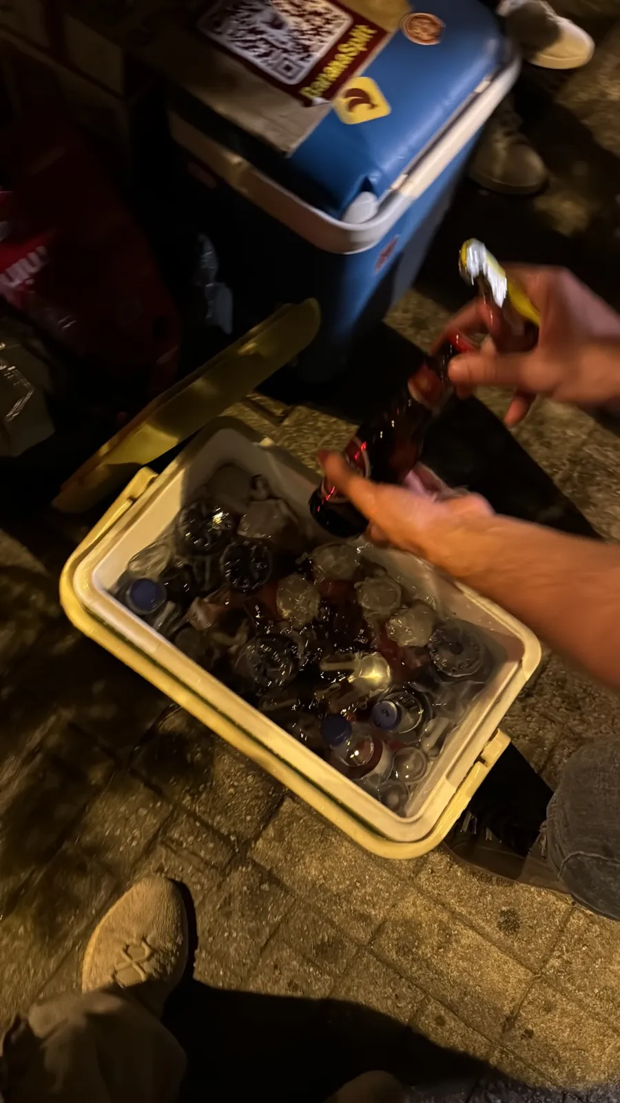 Nevera abierta con botellas en hielo y una mano sacando una bebida