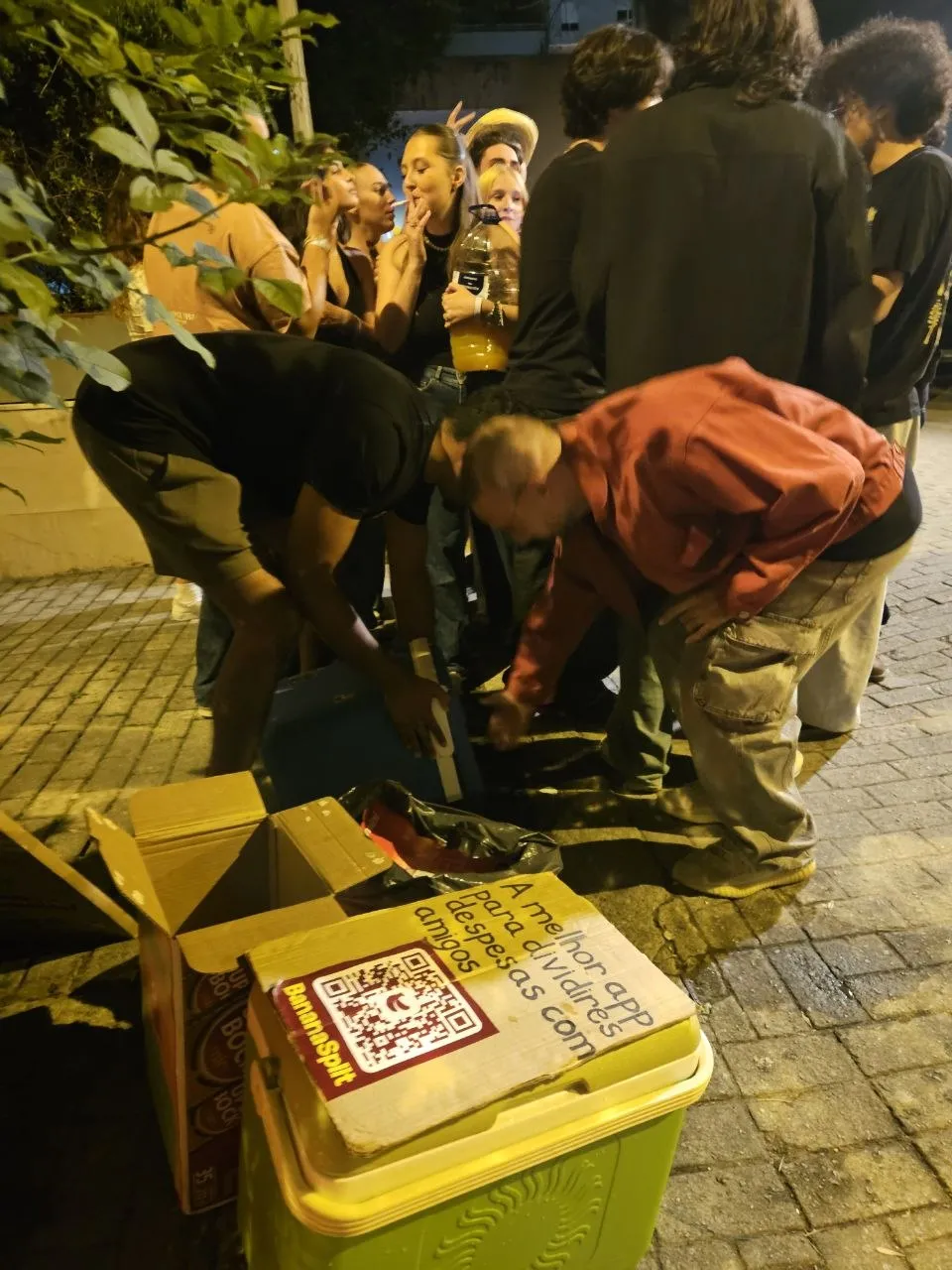 Dos miembros del equipo de BananaSplit inclinados sobre las neveras, sirviendo bebidas en medio de un grupo