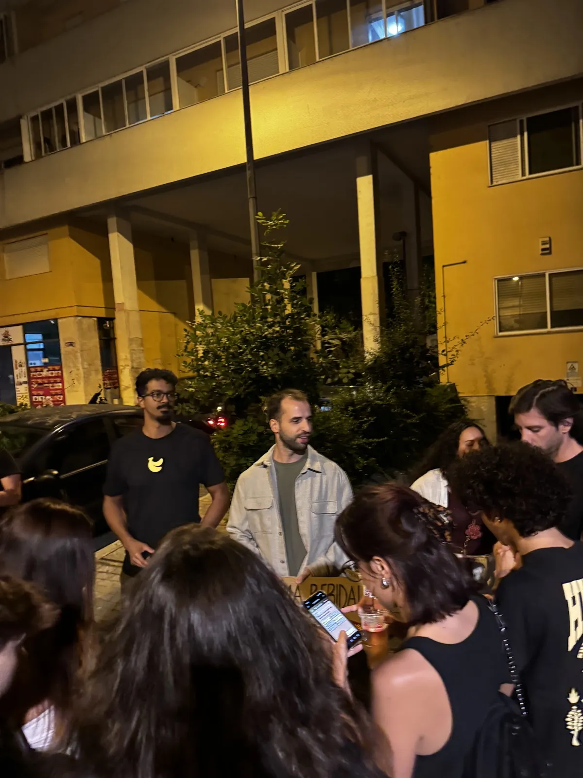 Gente alrededor del cartel de BananaSplit, con móviles en la mano, en la zona del Carpe