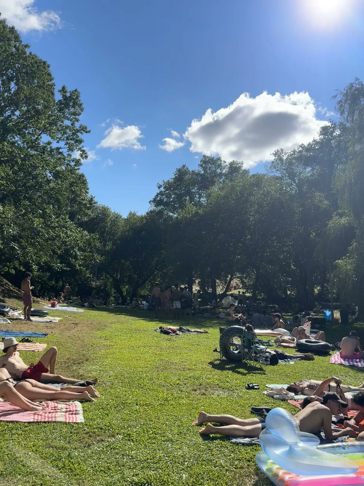 People resting in the sun by the river in Paredes de Coura