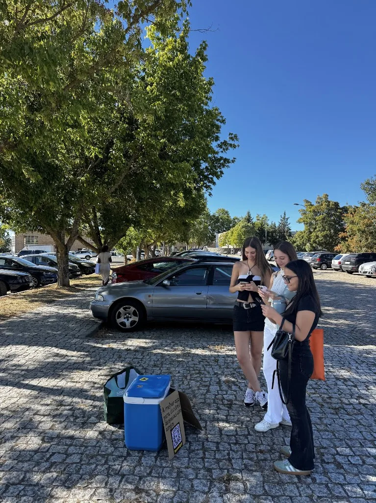 Três estudantes recebendo o kit de boas-vindas do BananaSplit e olhando para o app
